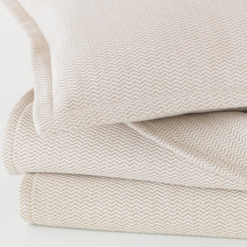 中性色调的诺勒系列，配以经典小巧的V形波浪纹，创造了一个完美豪华的盖毯和枕套组合。在葡萄牙编织完成，视觉与触觉的绝美搭配。